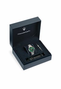 Coffret cadeau Maserati contenant une montre à cadran vert avec bracelet en acier inoxydable argenté, un bracelet en cuir noir et un outil argenté pour les ajustements.