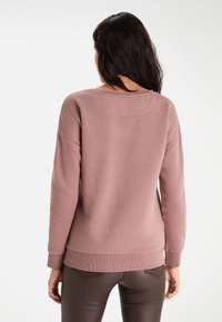 Lyse lilla sweatshirt med afslappet pasform, ribstrikkede manchetter og kant. Fremstillet af blødt stof med rund halsudskæring og enkel syning.