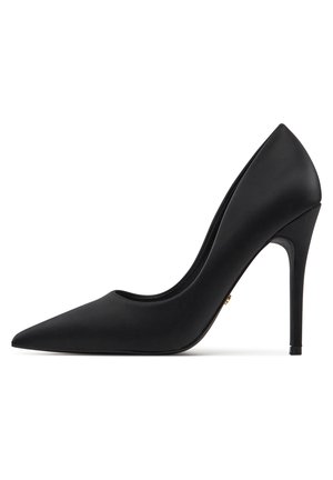 Décolleté nera con tacco alto a punta, finitura opaca liscia, silhouette elegante e tacco a stiletto sottile. Dettaglio accentato in oro visibile.