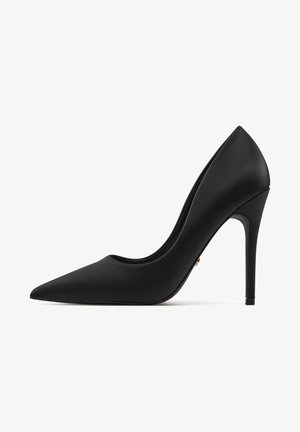 Schwarzer Pumps mit hohem Absatz, spitzer Zehenpartie, glattem mattem Finish, schlanker Silhouette und dünnem Stiletto-Absatz. Goldfarbene Akzentdetails sichtbar.