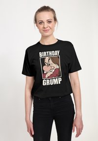 T-shirt nera in cotone con una stampa grafica di un personaggio dei cartoni animati con caratteristiche esagerate, con la scritta "BIRTHDAY GRUMP" sottostante.