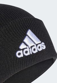 Czarna dzianinowa czapka z wywijanym brzegiem, z uszkami i haftowanym białym logo Adidas z trzema diagonlanymi paskami.