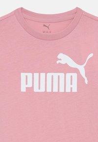 Růžové bavlněné tričko s bílým logem "PUMA" a grafikou skákající kočky. Kulatý výstřih a krátké rukávy s hladkou texturou.