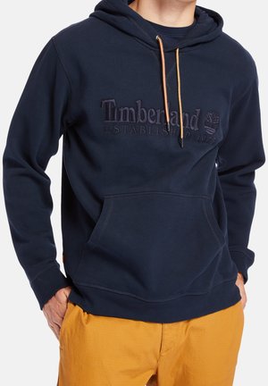 Hoodie bleu marine avec cordon de serrage ajustable, poche kangourou à l'avant et logo 'Timberland' embossé, fabriqué en matériau en coton doux.