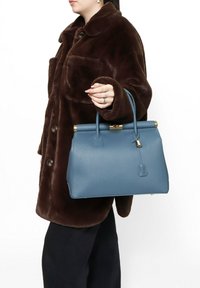 Blauwe leren handtas met een gestructureerde vorm, gouden hardware en slotdetail. De handgreep is kort en de tas heeft een textuurafwerking.