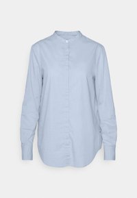 Ljusblå långärmad skjorta med mandarin-krage och dold knäppning, uppvisad mot en helt vit bakgrund.