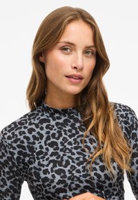 Long-sleeve top in gray with a black leopard print pattern. Features a high neckline and soft fabric texture.