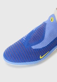Niebieskie i fioletowe dzianinowe sneakersy z żółtymi logo Nike w kształcie charakterystycznego „swoosha”, z prążkowaną teksturą i jasnoniebieską podeszwą.
