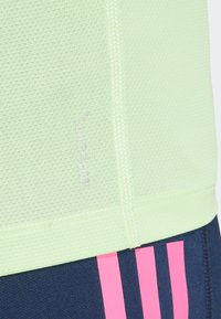 Vihreä limen värinen urheiluopas, jossa on hengittävä pinta. Varustettu ClimaCool -brändillä, litteillä saumoilla ja kontrastivärisellä tummansinisellä alaosalla, jossa on vaaleanpunaisia raitoja.