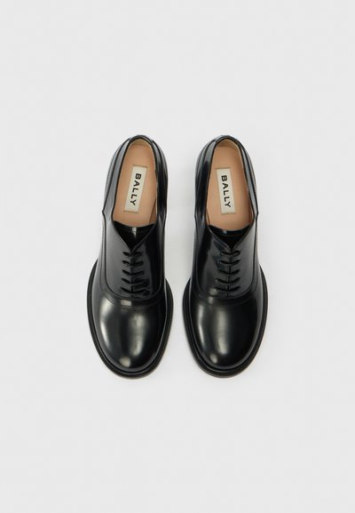 Black leather shoes with a smooth finish, round toe, and lace-up design. Includes a textured sole and a beige insole with the brand name.