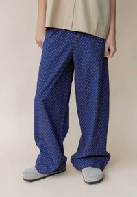 Marineblaue, lässige Hose mit weißen Punkten. Aus leichtem Stoff gefertigt, mit einem elastischen Bund und weitem Bein.