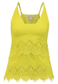 Haut sans manches jaune avec un décolleté en V, ourlet en dentelle superposée et tissu lisse. Présente des motifs délicats semblables à du crochet en bas.