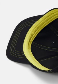 Black cap with a curved brim, featuring bright yellow stitching and a lined interior. The texture appears smooth with a structured design.