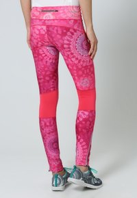 Leggings rosa a fantasia con un design vivace, caratterizzati da un pannello rosa a tinta unita sul polpaccio, realizzati in materiale elasticizzato.