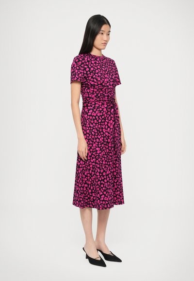 Sukienka w kwiaty z dopasowaną górą, krótkimi rękawami i zwiewną spódnicą. Przeważająca różowa kolorystyka z czarnymi akcentami i kwiatowymi wzorami.