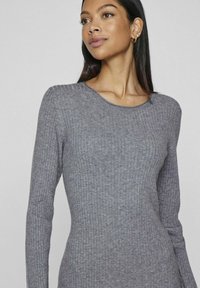 Gray ribbed long-sleeve sweater with a round neckline, featuring a soft texture and fitted silhouette, emphasizes a streamlined design.