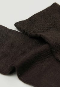 Calze lavorate a maglia marroni con una consistenza liscia e polsini a coste, caratterizzate da un design senza soluzione di continuità e tessuto morbido per il comfort.