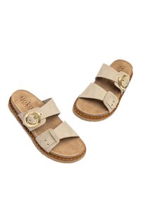 Sandali in suede beige con due larghe cinghie, dotati di una fibbia dorata e di borchie ai lati, e una suola imbottita marrone.