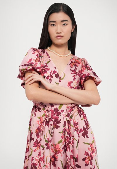 Rochie florală roz cu mâneci bufante, cu decolteu în V și talie cu șnur. Materialul prezintă modele florale mari în nuanțe de burgundy și verde.