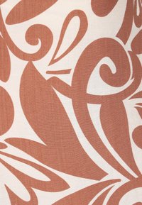 Stof met een beige achtergrond en grote, abstracte krullen in een diep roestkleur. De textuur lijkt glad en een beetje linnenachtig.
