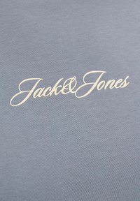 Ανοιχτό μπλε ύφασμα με το λογότυπο «Jack & Jones» τυπωμένο με λευκά καλλιγραφικά γράμματα στο κέντρο.