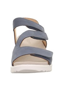 Blå lædersandal med tre justerbare Velcro-remme, en beige polstret fodseng og en hvid gummiydersål.