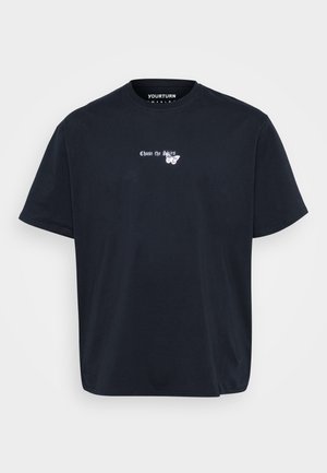 T-shirt en coton bleu marine avec col rond. Présente un texte blanc "Chase the Skies" et un motif de papillon à l'avant. Coupe ample.
