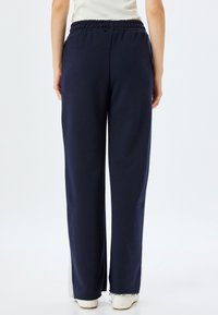 Marineblauwe sweatpants met een trekkoord in de taille, relaxte pasvorm en zijsplitten bij de enkels. Gemaakt van zachte, gestructureerde stof.