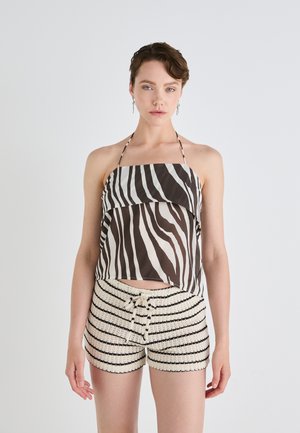 Stribet halterneck-top i brunt og creme, parret med creme shorts med sorte vandrette striber og snoreliv.