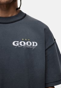 Szara bawełniana koszulka z krótkim rękawem. Posiada białe logo "GOOD", szare napisy "For Nothing" oraz trzy złote gwiazdki nad tekstem.