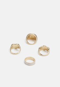 Quatro anéis de ouro com vários designs: dois robustos, um com uma banda lisa e acento branco, e um com uma textura decorativa.