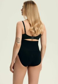 Czarny kombinezon wyszczuplający z regulowanymi ramiączkami, zapięciem na haftki z tyłu oraz gładką teksturą, prezentujący wysoki krój nogawek.