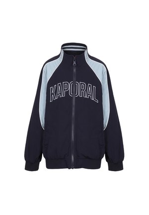 Marineblå zip-up jakke med "KAPORAL" logo i hvid. Har lyseblå skulderpaneler samt ribbede manchetter og kant for et tætsiddende look.