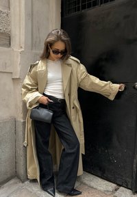 Beež mantli laiade varrukatega ja vöödiga, mustad kõrge vöökohtadega teksad, terava musta kontsaga kingad ja väike must käekott.