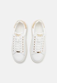 Sneakers bianche con accenti dorati e design con lacci, caratterizzati da una superficie in pelle liscia e una targhetta con il marchio sulla linguetta.