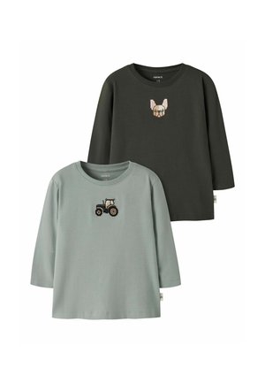 Deux chemises longues manches pour enfants, une vert foncé avec une broderie tête de chien, et une vert clair avec une broderie tracteur sur la poitrine.