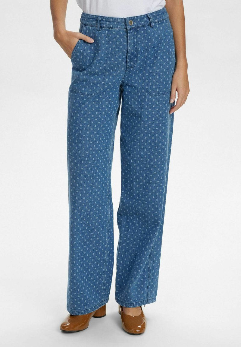 Šviesiai mėlynos džinsinės kelnės su baltomis taškeliais, plačios kojos dizainas, priekinės kišenės ir mygtuko užsegimas juosmens srityje.