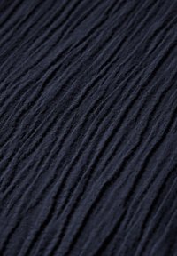 Geweven marineblauwe stof met een gekreukt oppervlakpatroon. Zacht materiaal met zichtbare rimpels en variërende dieptes. Geschikt voor kleding.