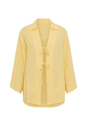 Κίτρινη, ελαφριά μπλούζα με γιακά, ανοιχτό μπροστινό μέρος και δύο κορδόνια μπροστά. Διαθέτει μακριά, φαρδιά μανίκια και άνετη εφαρμογή.