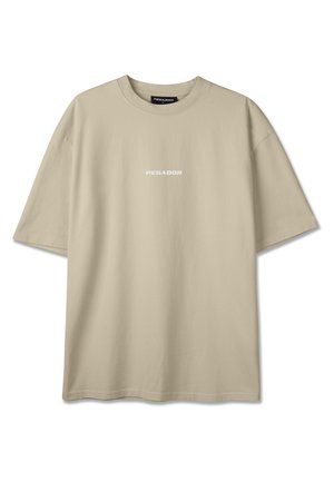 Béžové oversize tričko s krátkými rukávy, kulatým výstřihem a malým bílým logem „PEGADOR“ uprostřed na hrudi.