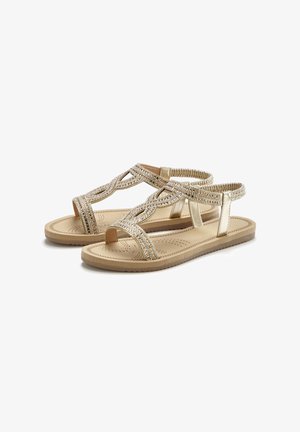 Beige flache Sandalen mit elastischem Knöchelriemen, mit geflochtenem und mit Strasssteinen verziertem T-Riemen-Design und leicht gepolsterter Sohle.