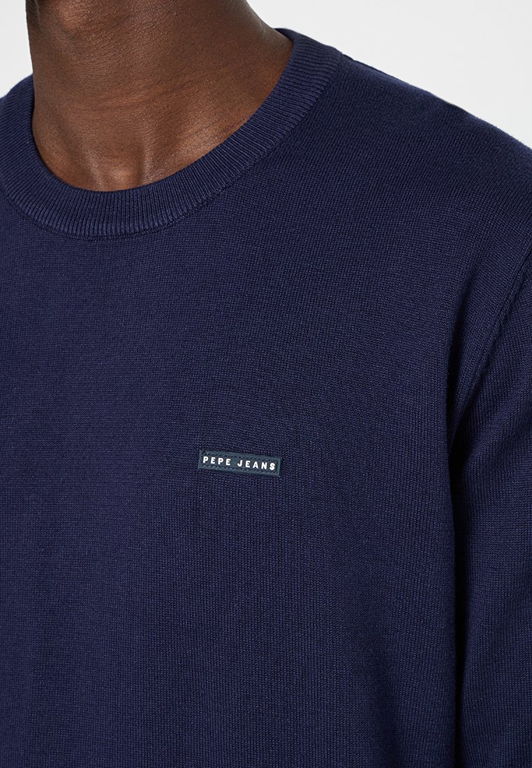 Granatowy sweatshirt z okrągłym dekoltem, dzianinową teksturą oraz małym prostokątnym logo Pepe Jeans na lewej piersi.