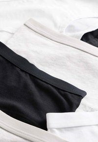 Tre T-shirt-kragar i svart, vitt och ljusgrått tyg. Mjukt bomullstextur med kontrasterande ribbkanter.