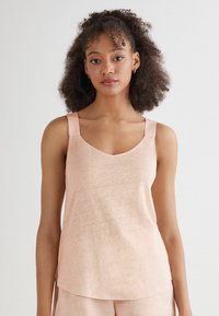 Ljusrosa ärmlös topp med V-ringning och breda axelband. Mjuk, lättviktig tyg med en slät textur och avslappnad passform.