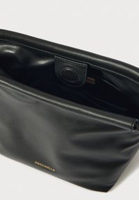 Borsa in pelle nera con finitura morbida e testurizzata. Presenta una chiusura a bottone e un logo dorato discreto. Interno scuro e spazioso.