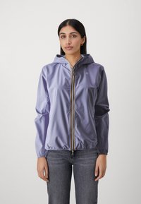 Veste de pluie légère violette avec capuche, fermeture éclair frontale, poignets et taille élastiques. Logo sur la poitrine et fermeture éclair contrastante.