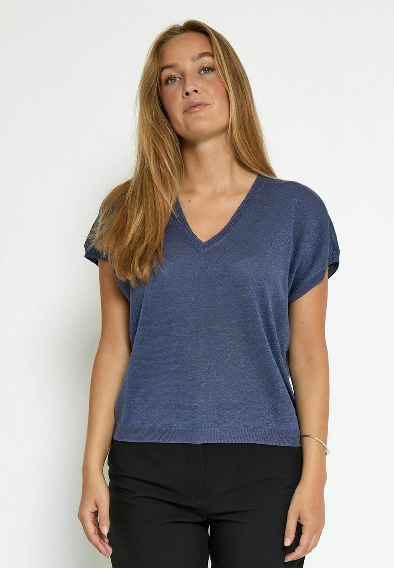 Džemper s V-izrezom i kratkim rukavima u tamnoplavoj pletenoj tkanini s blagim sjajem. Labav kroj s ravnim rubom, uparen s tamnim hlačama.