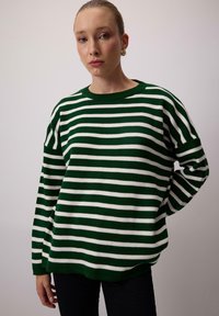 Green and white striped sweater with a crew neckline, loose fit, and ribbed cuffs. Features a soft, textured knit fabric.