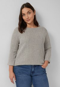 Lichtgrijs gebreid sweater met een gestructureerd oppervlak, ronde halslijn en driekwart mouwen, gecombineerd met blauwe denim jeans.