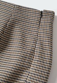 Tissu en mélange de laine avec un motif pied-de-poule en marron, beige et bleu marine. Comprend un détail de fermeture éclair en haut.